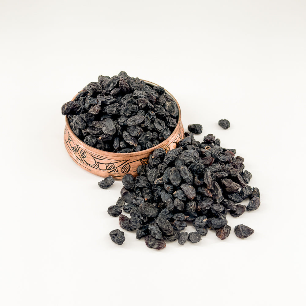 Bakır kapta sunulan doğal, kuru çekirdeksiz siyah üzümler.