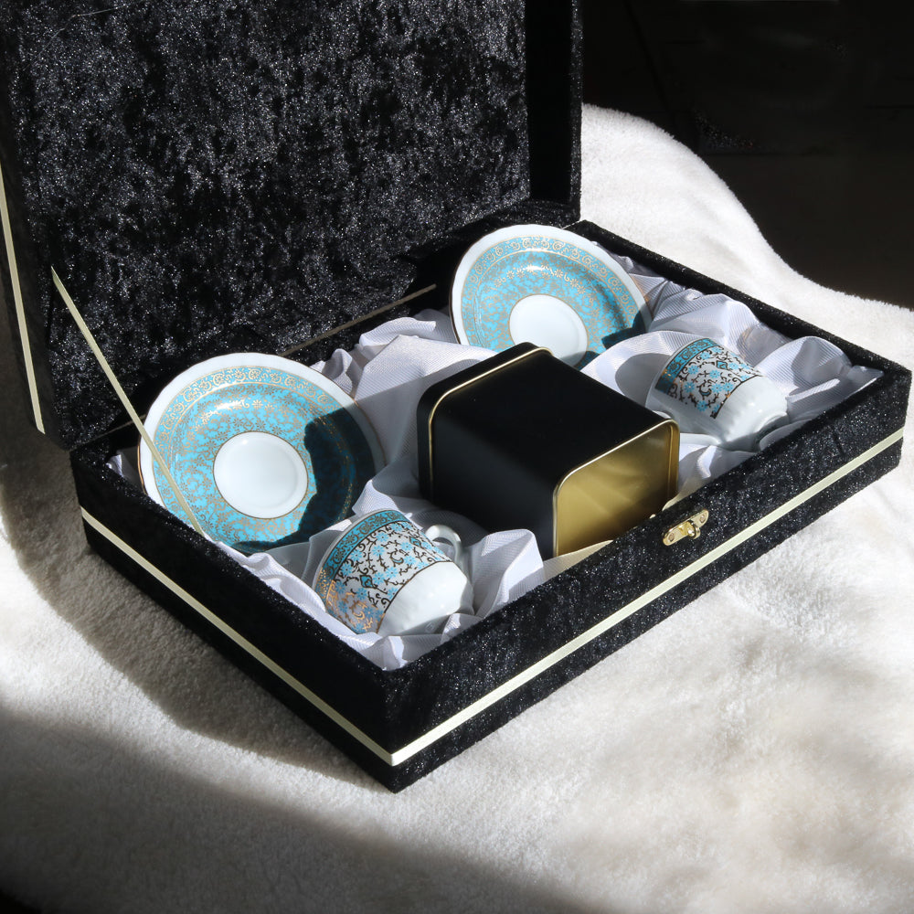 Siyah kutuda sunulan, altın ve mavi desenli porselen fincanlar ve tabaklar, metal saklama kabıyla birlikte.