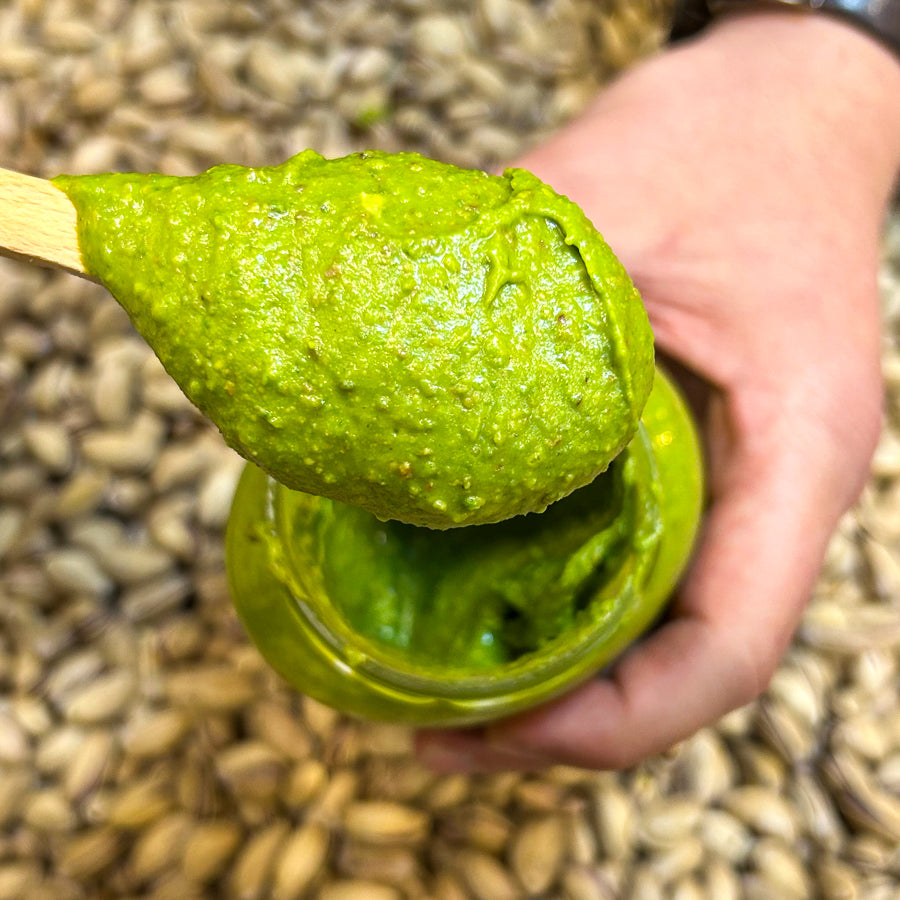 Bir kaşık üzerinde duran, yoğun kıvamlı ve sürülebilir kahvaltılık Antep fıstık ezmesi.