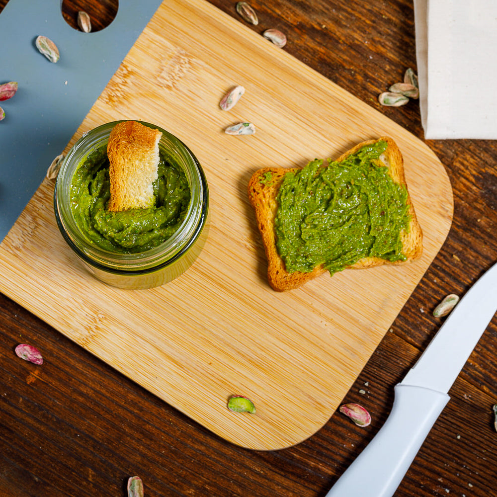 Cam kavanozda, pürüzsüz ve doğal yeşil renkte Antep fıstık ezmesinin yakından çekilmiş görüntüsü.