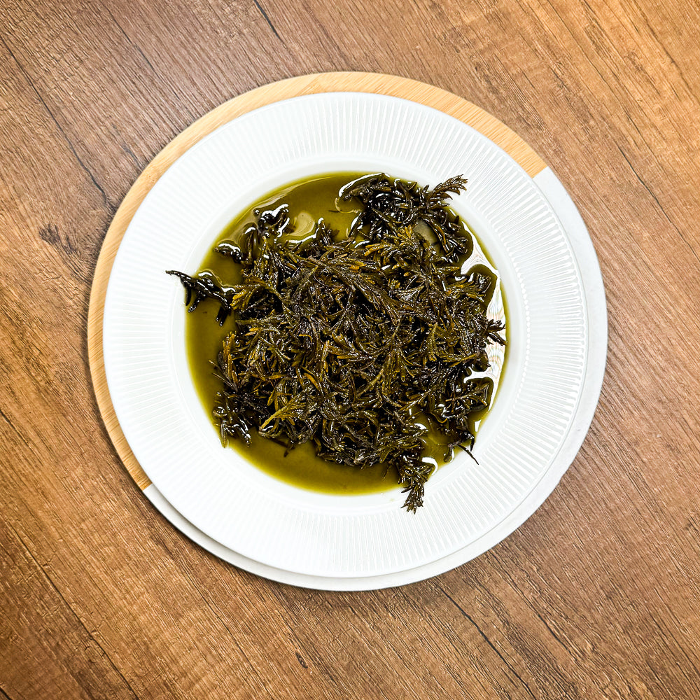 Beyaz tabakta zeytinyağı içinde marine edilmiş dağ kekiği.